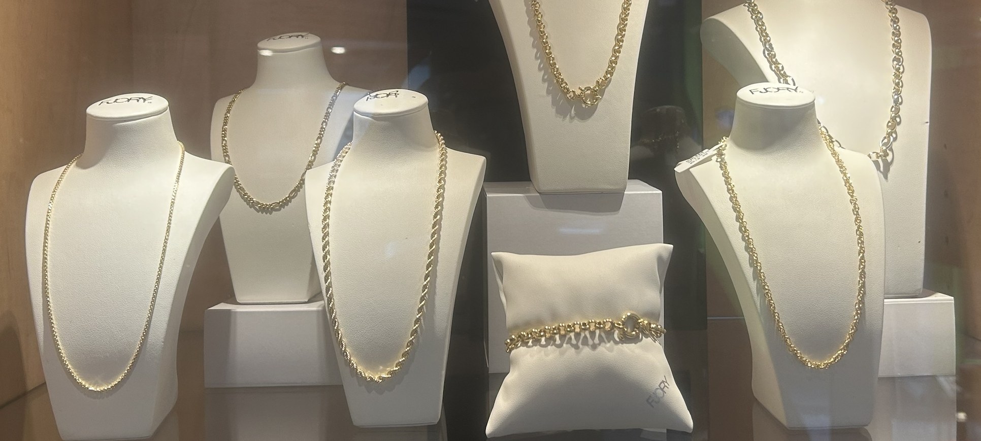 Gouden kettingen op witte paspoppen in de vitrine