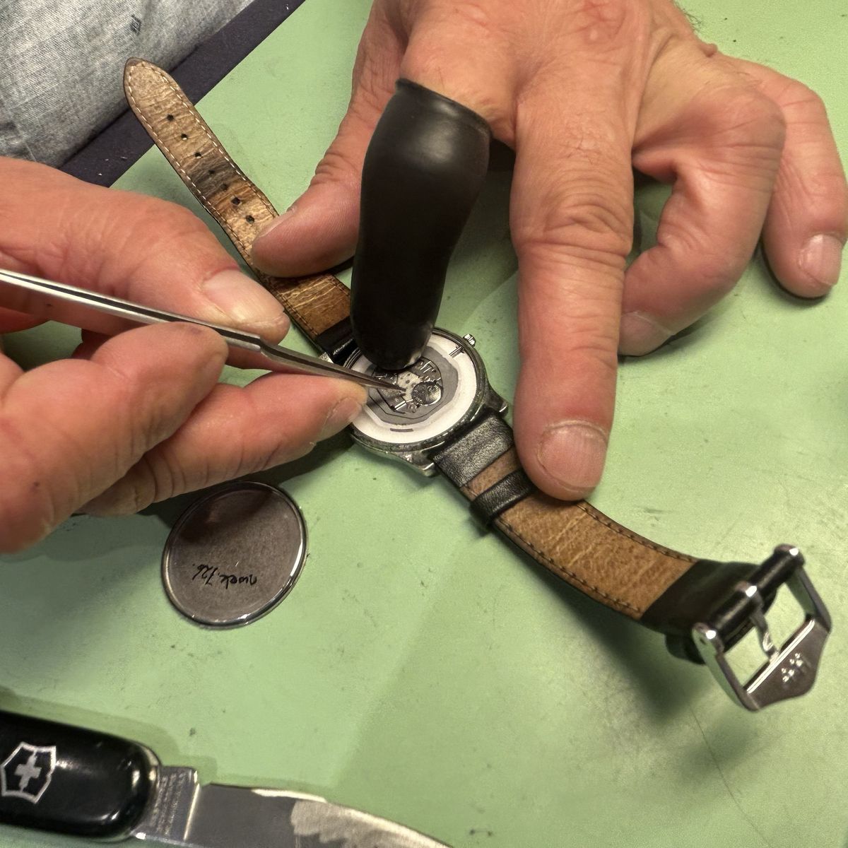 Met een pincet wordt een open horloge gerepareerd op de werkbank